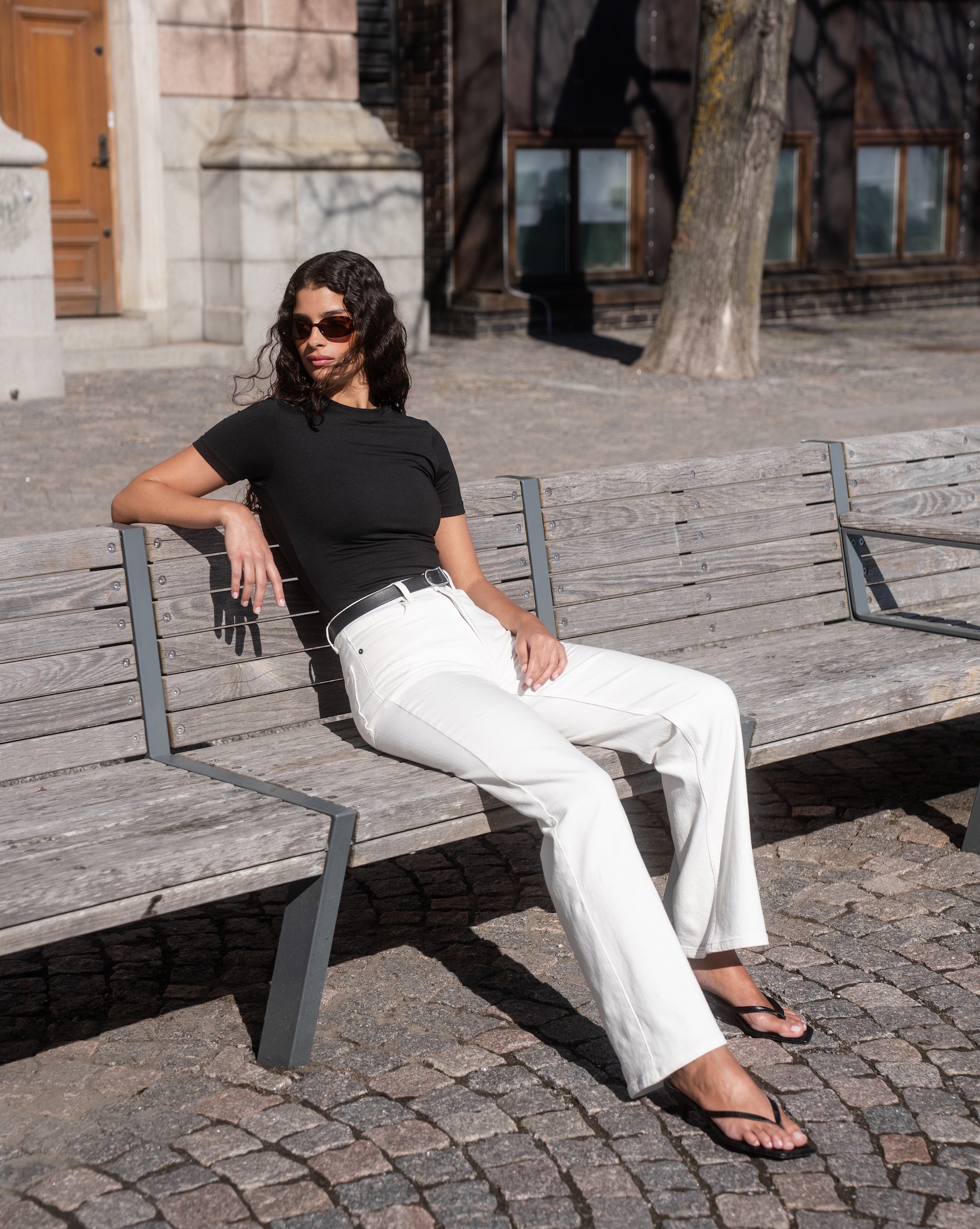 A woman wearing a black soft top styled with white Summer ComfortDenim jeans by Ninepine for a clean Scandinavian-inspired outfit.