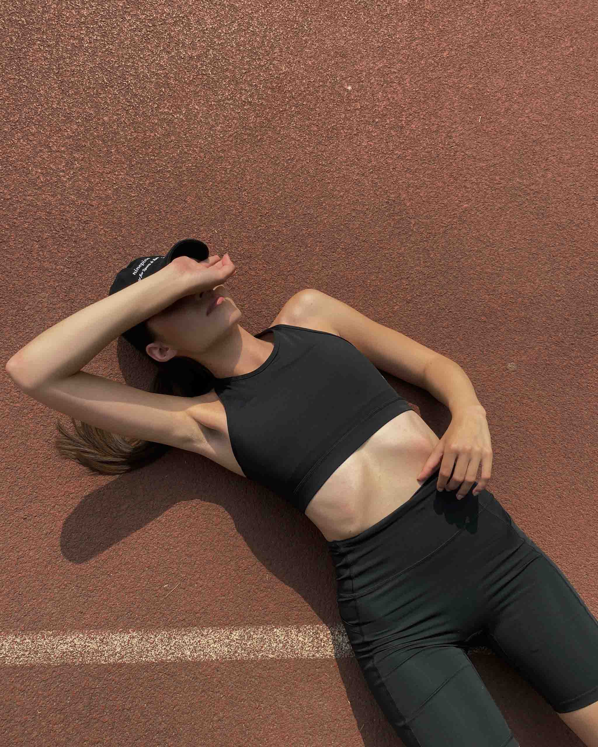 Girl in ninepine activewear set lying on back on a running track